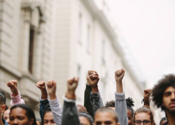 Arms raised in protest. Group of protestors fists raised up in the air.