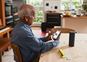 Senior man booking online appointment through mobile phone at Home